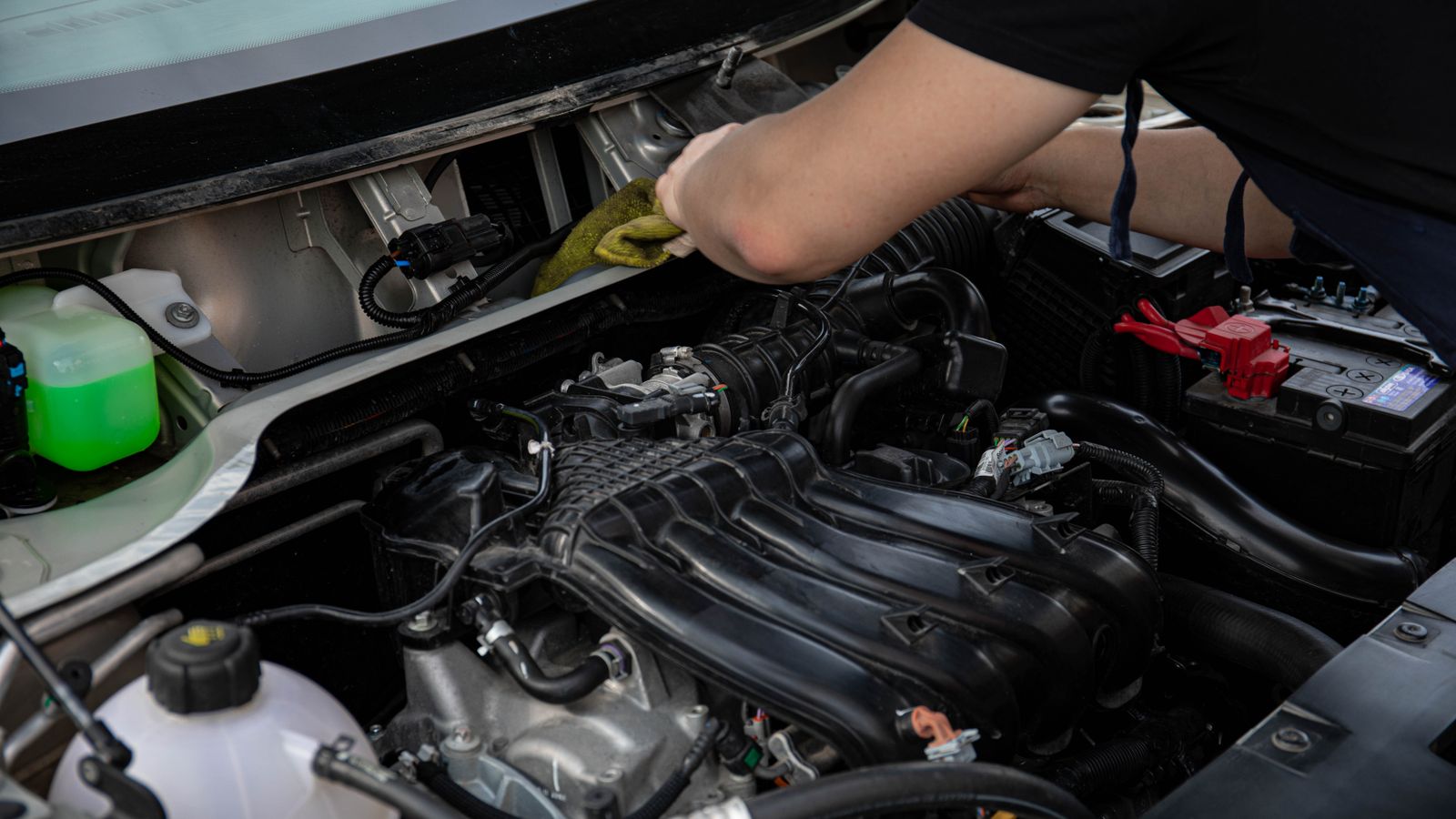 Técnico trabajando en el compartimiento del motor de un vehículo